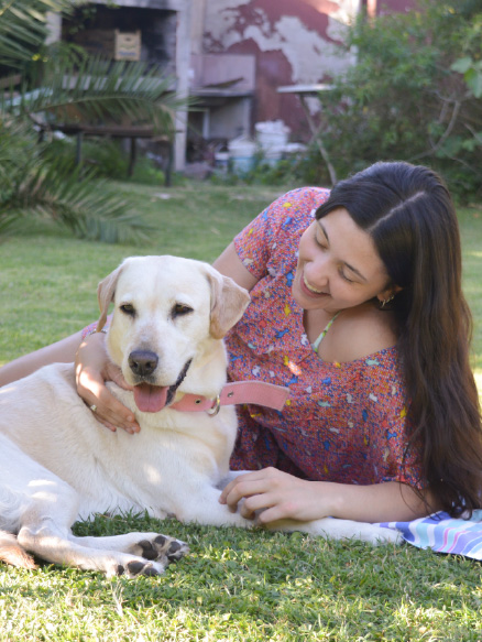 recostada en el pasto con una perra labrador
